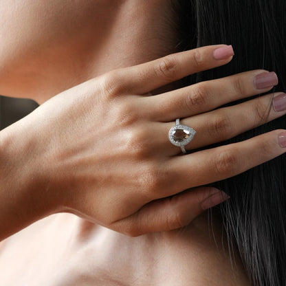Woman with long dark hair touching her neck, wearing jewelry indoors.