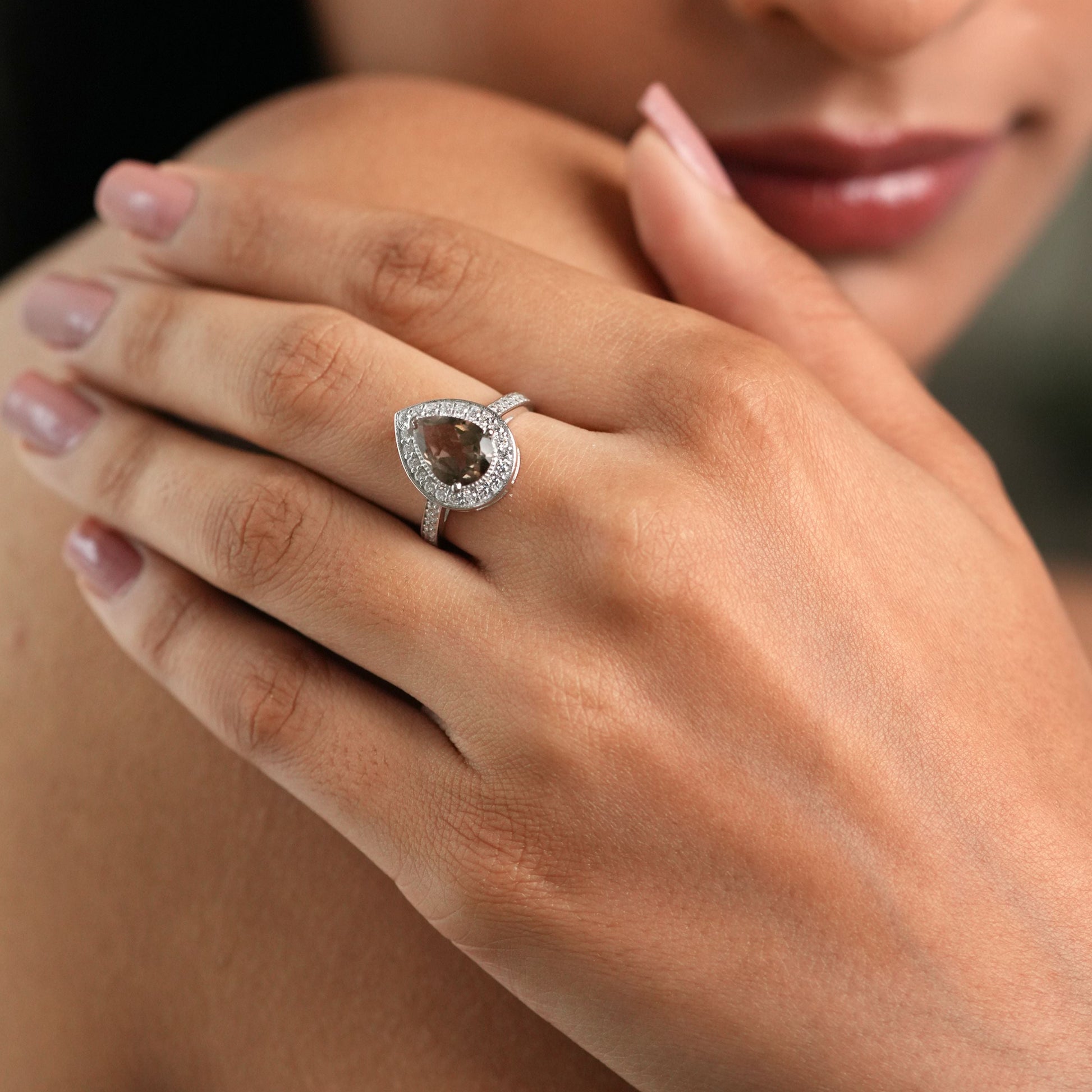 Close-up of a woman's hand wearing a diamond ring with a blurred background