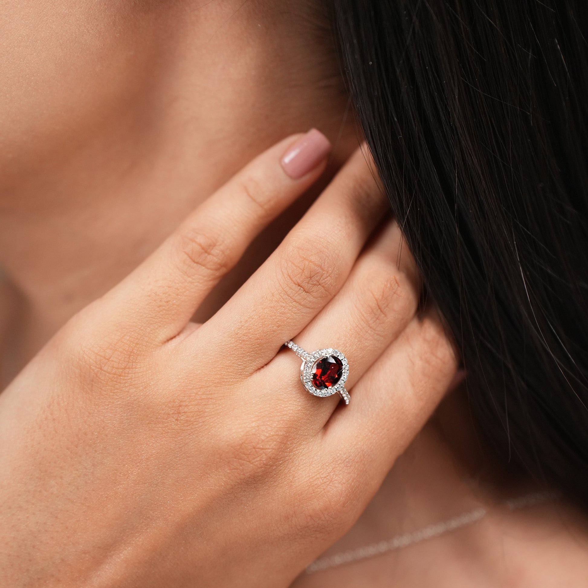 Close-up of a woman wearing a ring and earrings with gemstones.