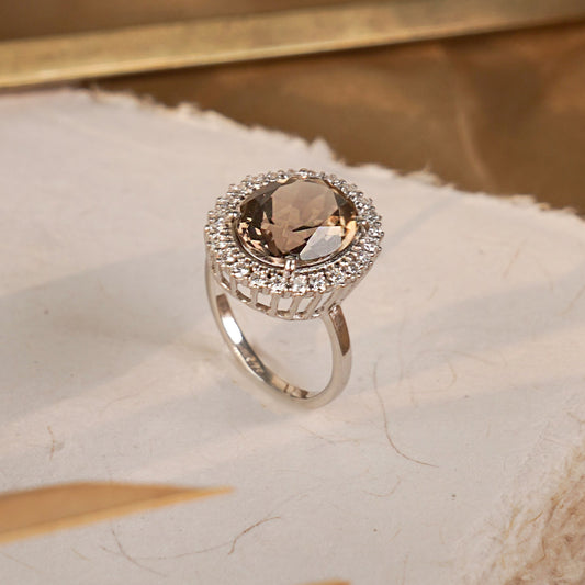 Ring with a brown gemstone and diamond accents on a marble surface