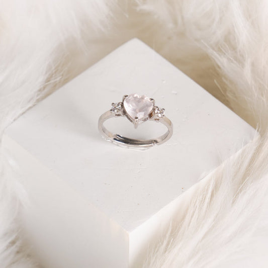 A heart-shaped rose quartz ring with cubic zirconia accents on a silver band.