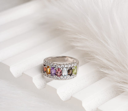 Silver ring with multicolored gemstones on a white feather background