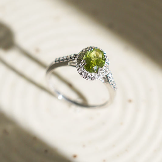 A Petite Natural Peridot Ring with a silver band and halo design.