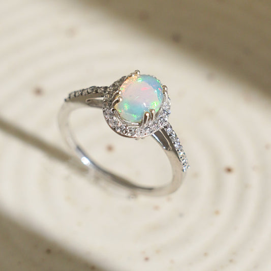 A white ceramic plate with a Ethiopian opal halo ring kept on it.