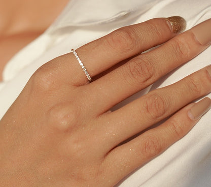 Close-up of a hand wearing a delicate ring on a plain background