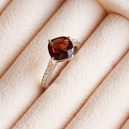 A   gold ring with a diagonally set garnet gemstone.