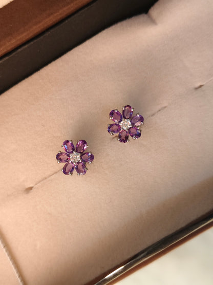 Pair of purple flower-shaped earrings on a soft surface