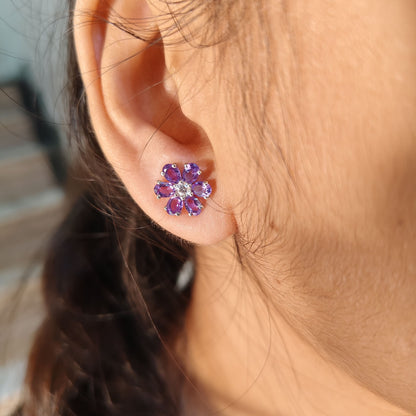 Close-up of an ear wearing a floral purple earring with blurred background