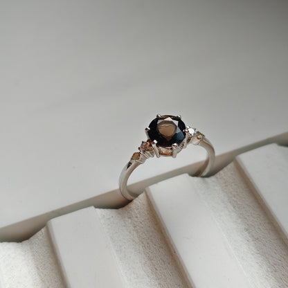 Ring with a dark gemstone on a textured white surface