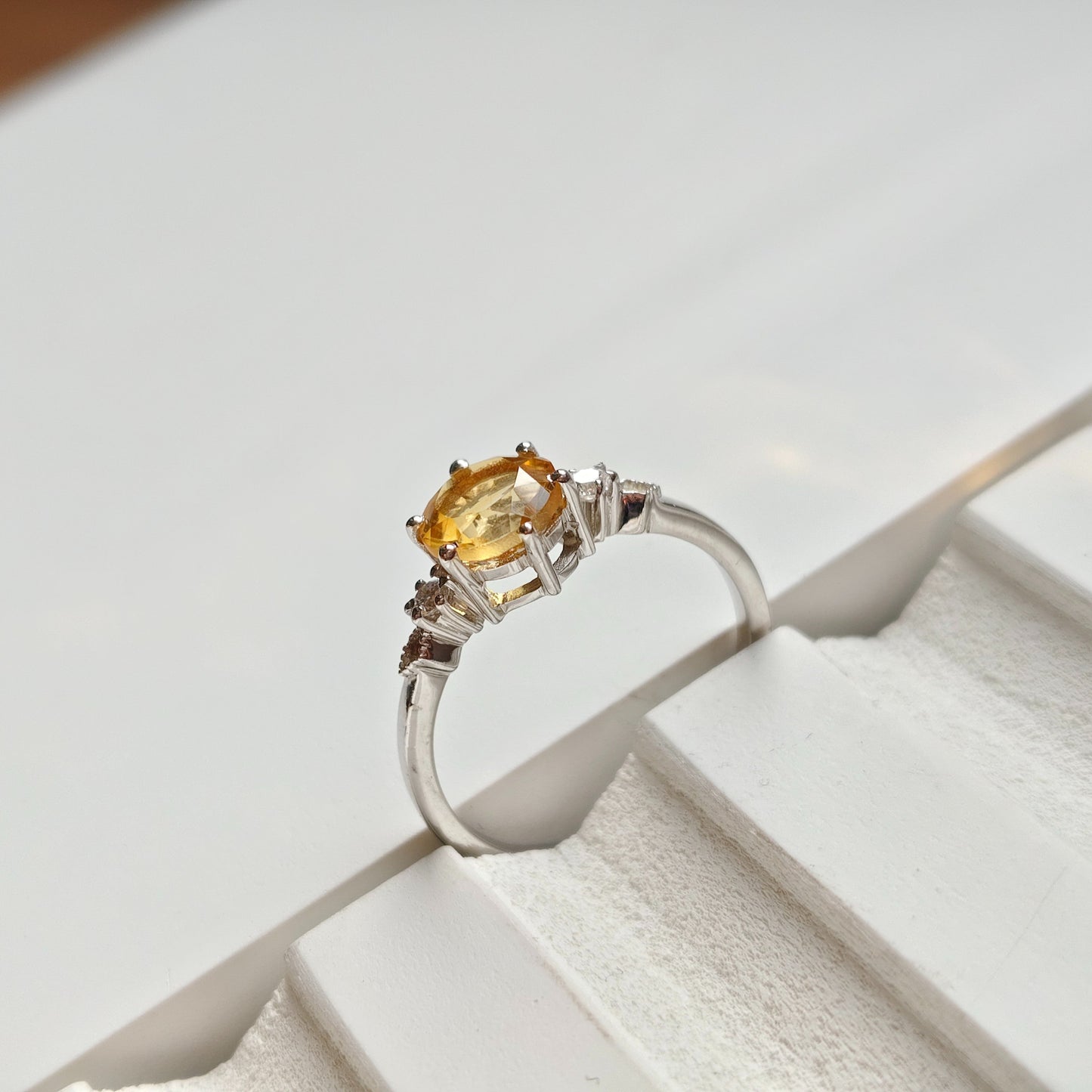 Silver ring with a yellow gemstone on a white surface