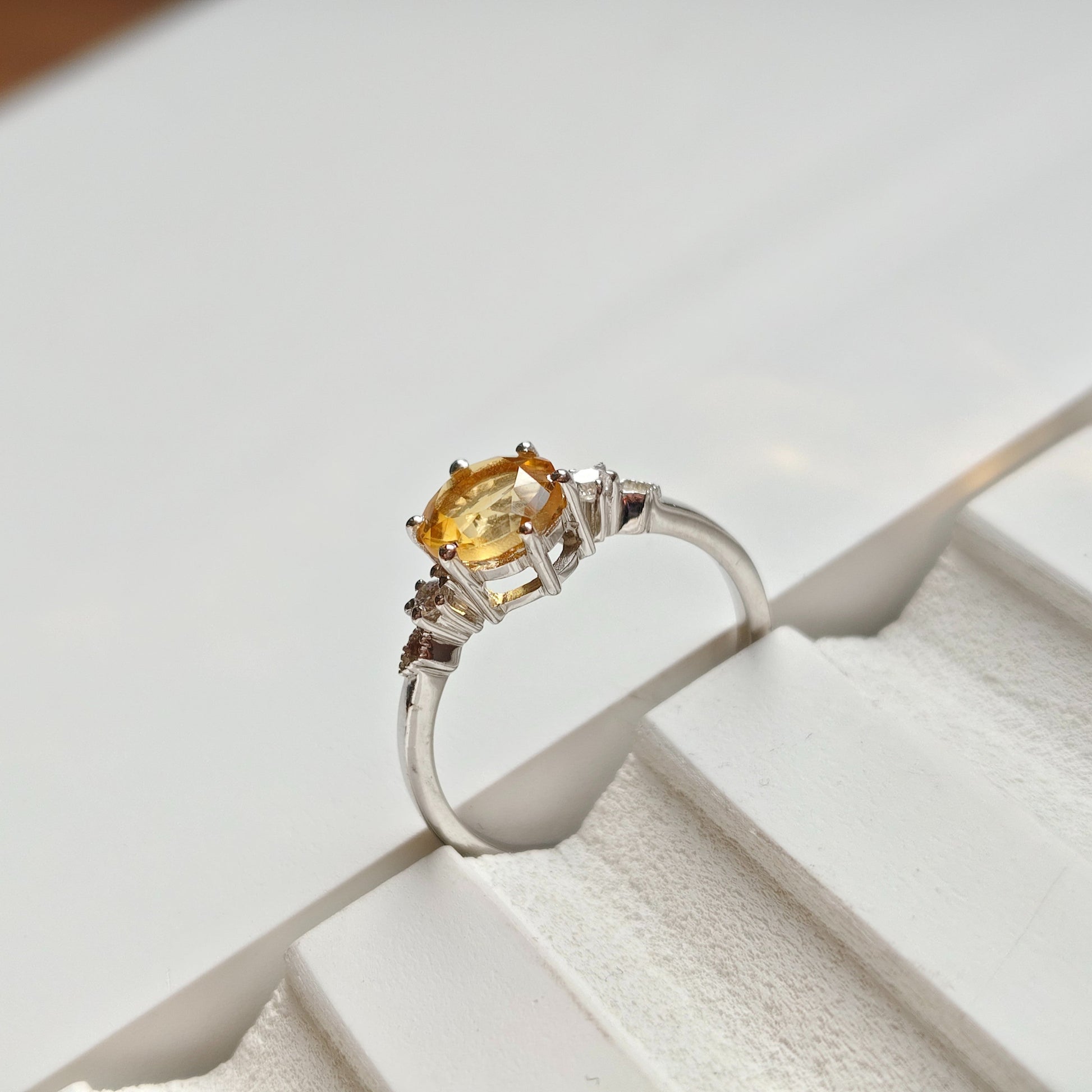 Silver ring with a yellow gemstone on a white surface