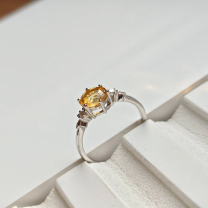 Silver ring with a yellow gemstone on a white surface