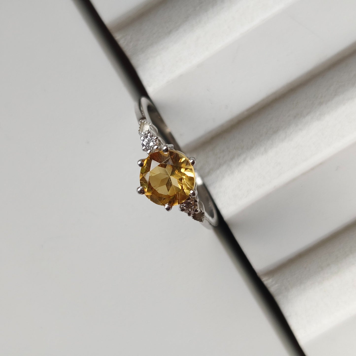 Ring with a yellow gemstone on a white surface