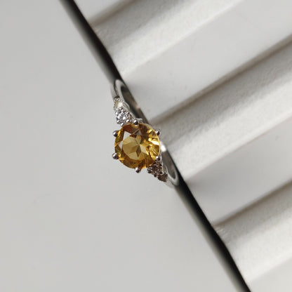 Ring with a yellow gemstone on a white surface