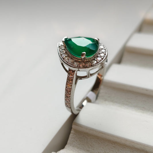 Silver ring with a green gemstone on a white surface