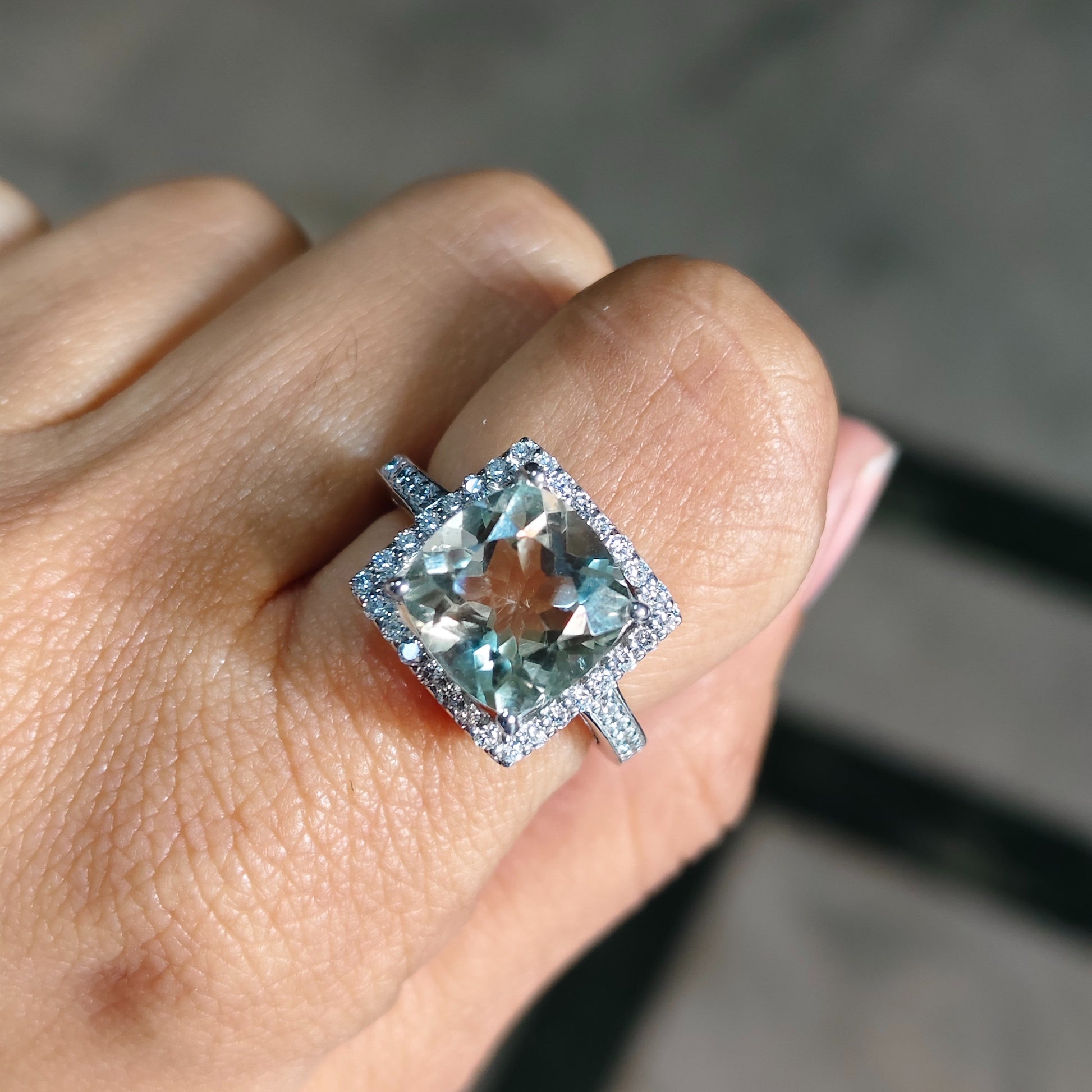Ring with a blue gemstone on a person's finger against a blurred background