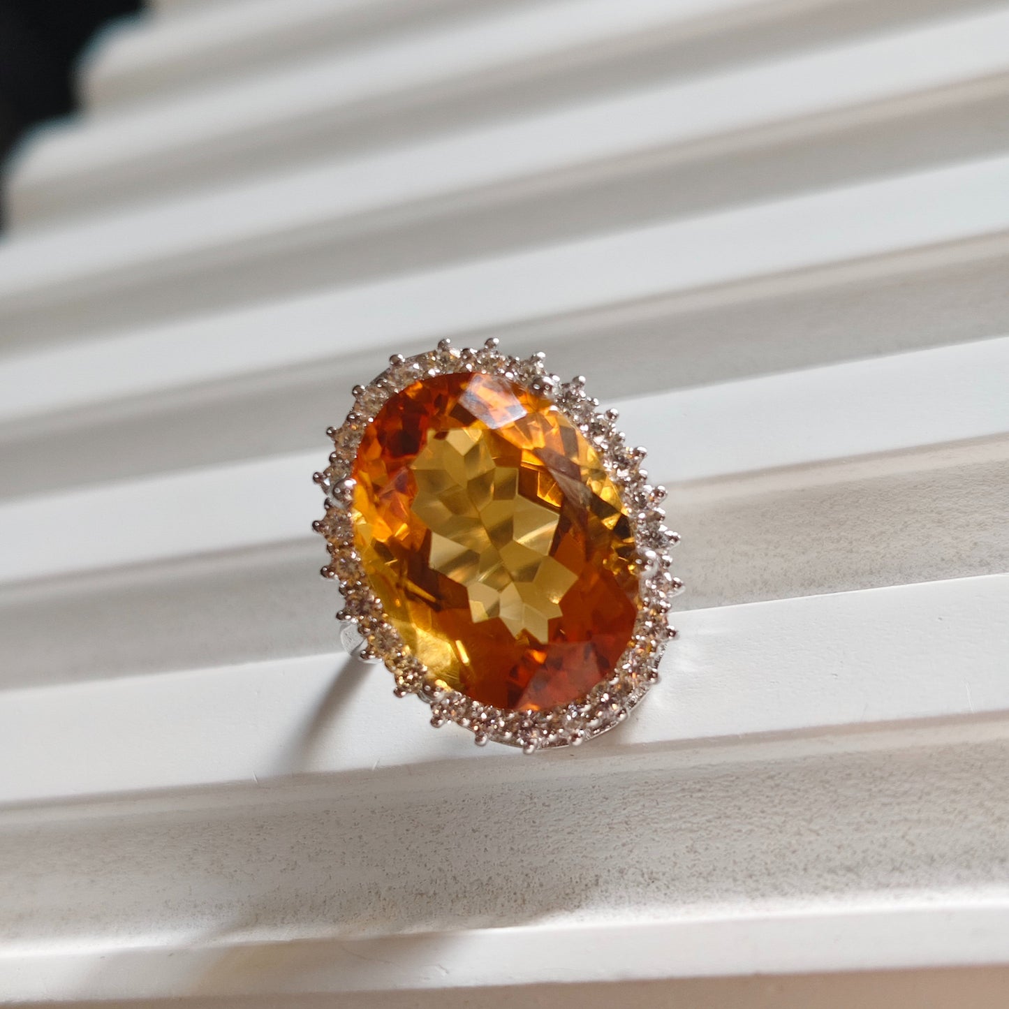 Ring with a large orange gemstone on a white surface