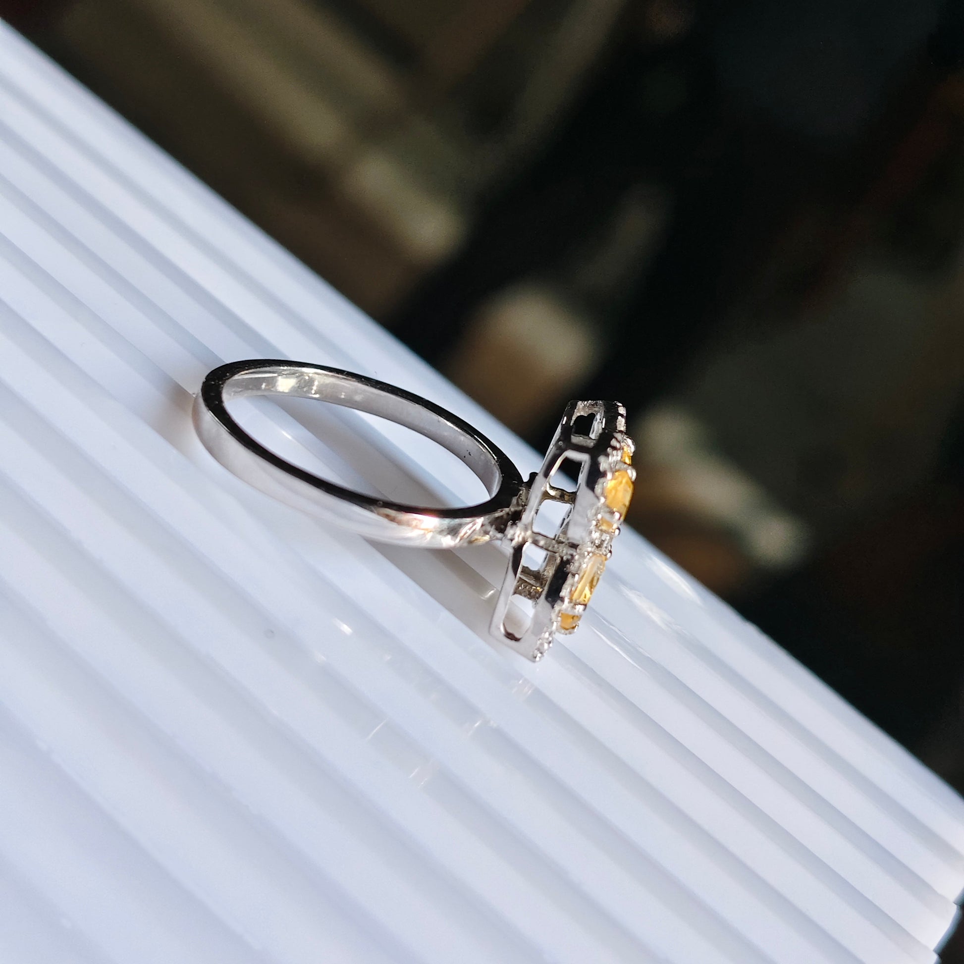 Silver ring with a yellow gemstone on a white surface