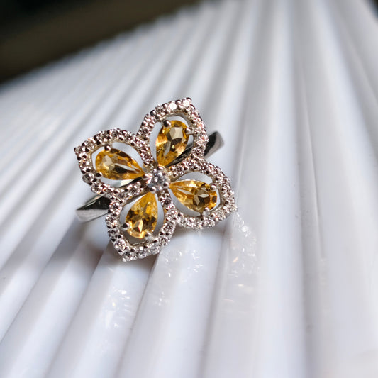 Butterfly-shaped ring with yellow gemstones on a white fabric background