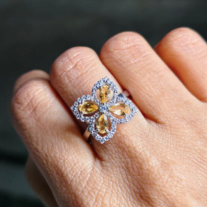 Close-up of a hand wearing a decorative ring with yellow gemstones.