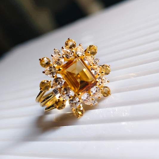Gold ring with a large yellow gemstone on a white surface