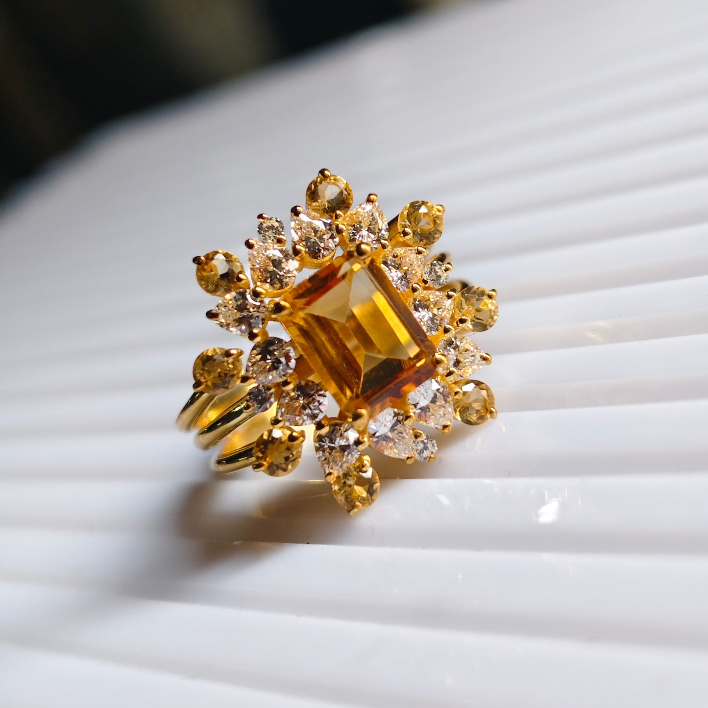 Gold ring with a large central gemstone and smaller stones on a white surface