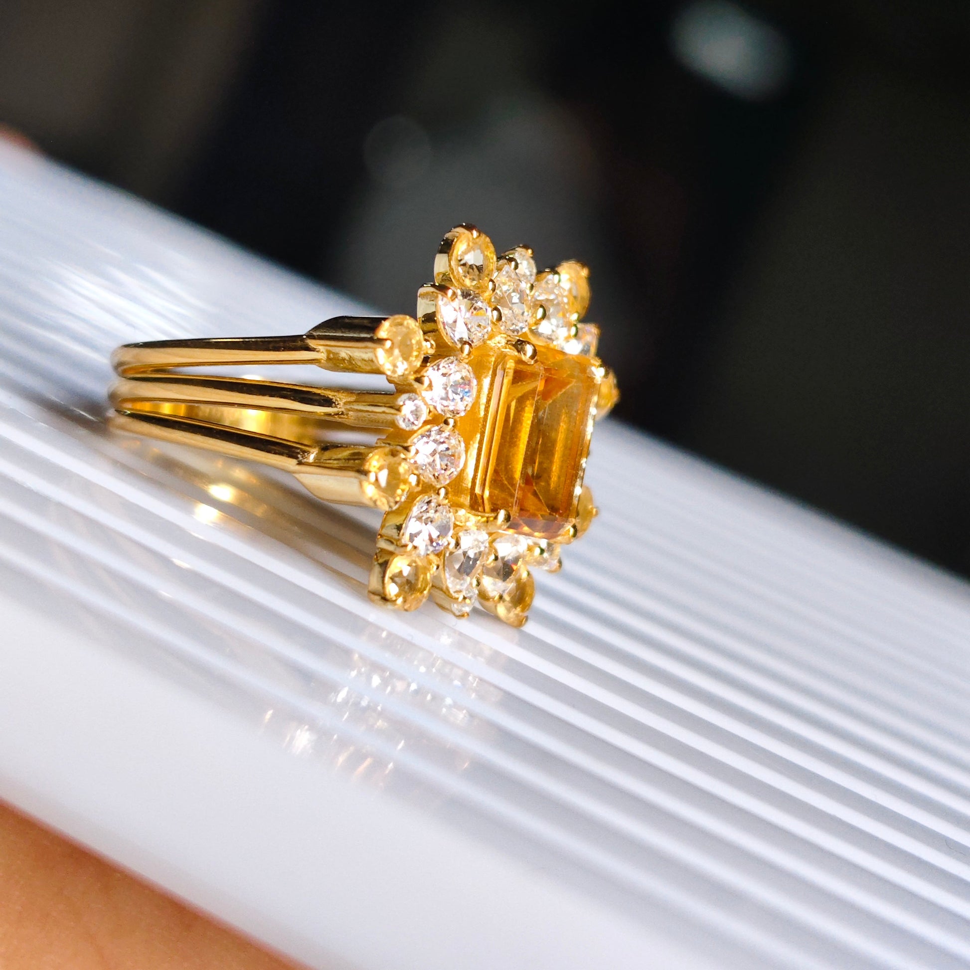 Gold ring with a central gemstone and smaller diamonds on a white surface