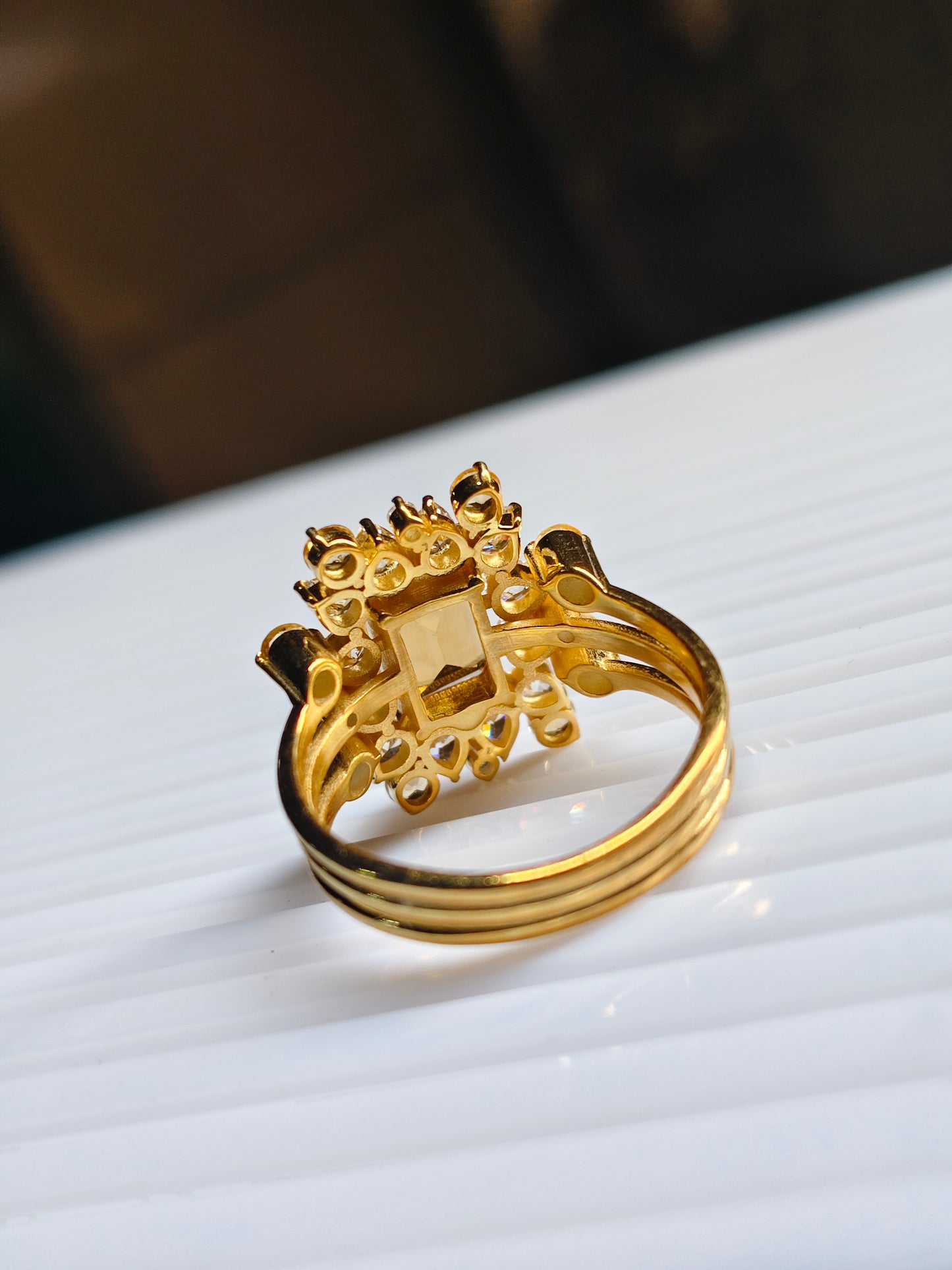 Gold ring with intricate design on a white surface