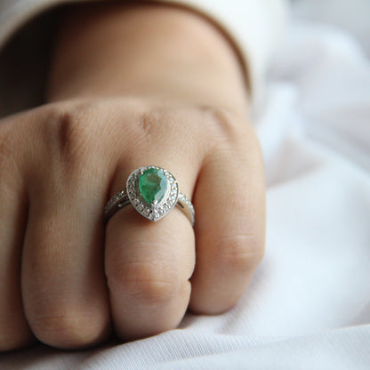 Close-up of a hand wearing a ring with a green gemstone on a white background