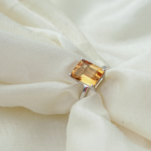 A silver ring with a large orange citrine gemstone.