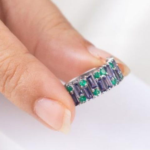a ring with purple and green gemstones on a white background